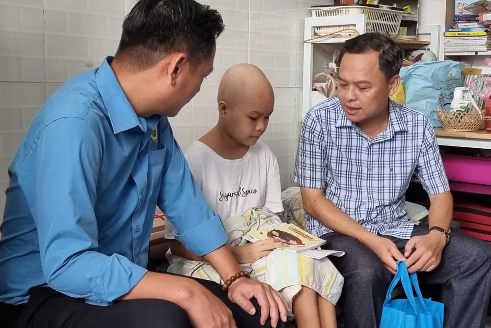 Ông Tống Duy Trương, Phó Chủ tịch Công đoàn cơ sở Báo SGGP (bìa phải) trao quà đến em Nguyễn Đào Thiên Khánh