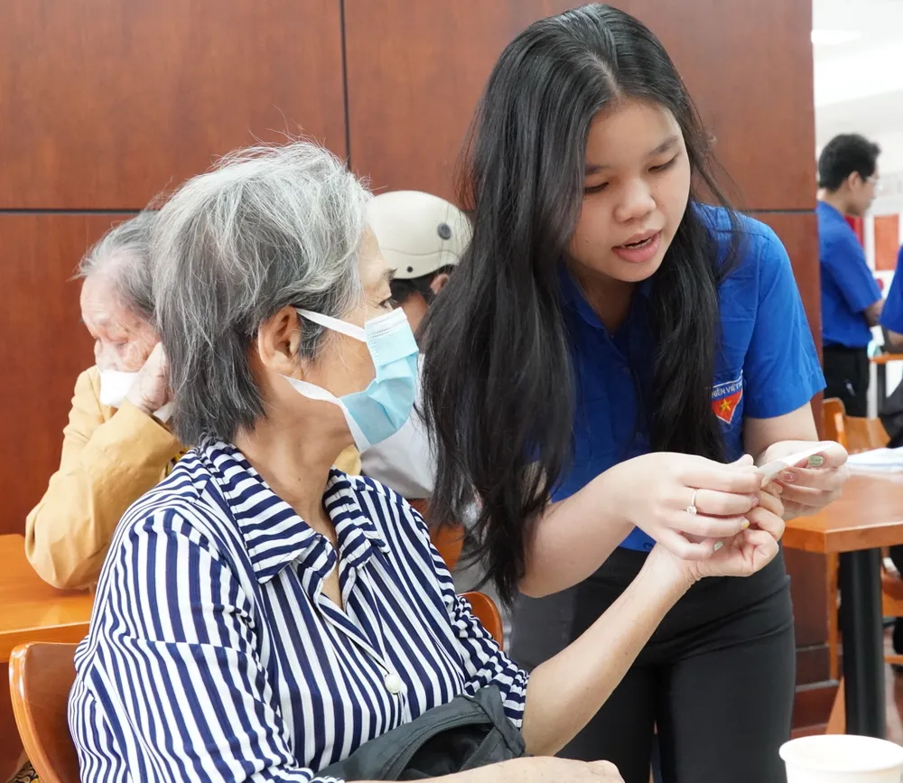 Đoàn viên thanh niên phường Tân Mỹ hướng dẫn người dân. Ảnh: THU HƯỜNG 6HH08738.JPG