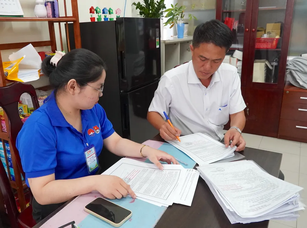 Phó Chủ tịch UBND phường Tân Thuận ngồi tại khu vực tiếp nhận thủ tục hành chính để ký hồ sơ, thủ tục hành chính. Ảnh: PHƯƠNG UYÊN 6HH09895.JPG