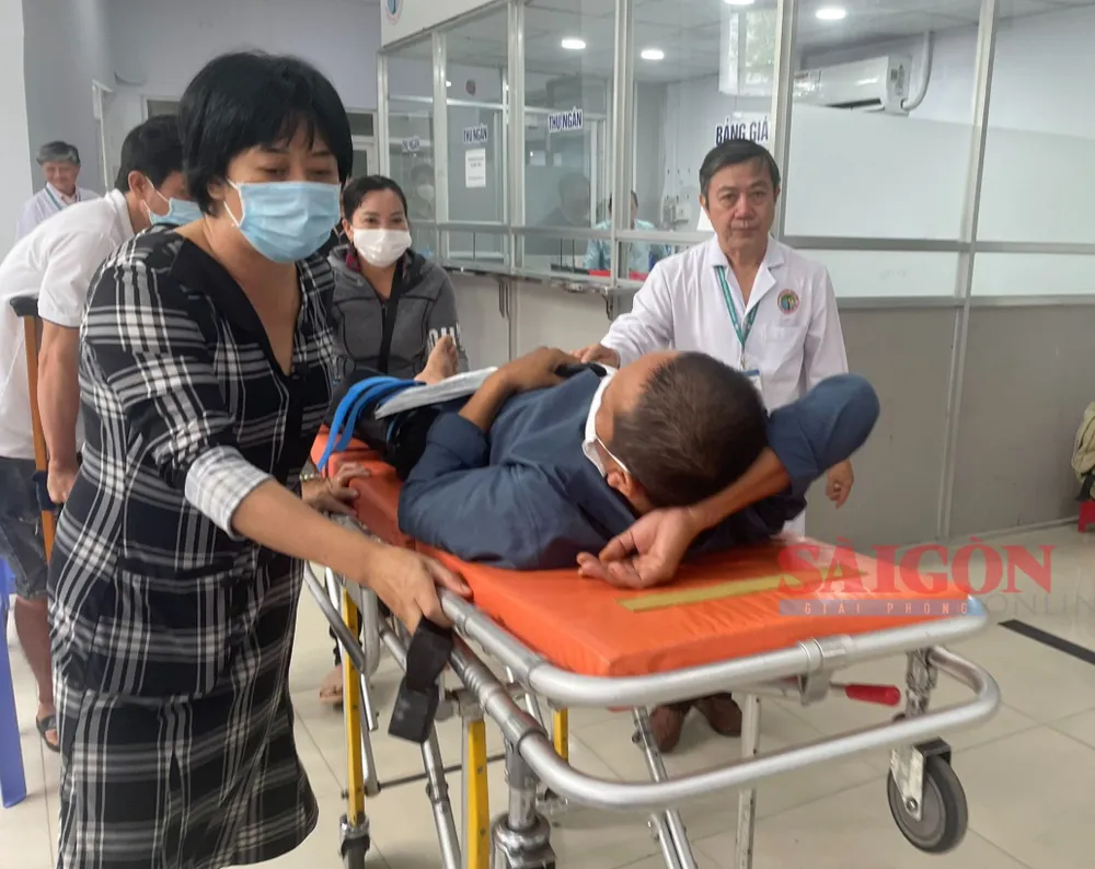 Bác sĩ Châu Văn Đính, Giám đốc Bệnh viện Chấn thương Chỉnh hình (bìa phải) vận chuyển người bệnh đi chụp Xquang Bác sĩ Châu Văn Đính, Giám đốc Bệnh viện Chấn thương Chỉnh hình (bìa phải) vận chuyển người bệnh đi chụp Xquang