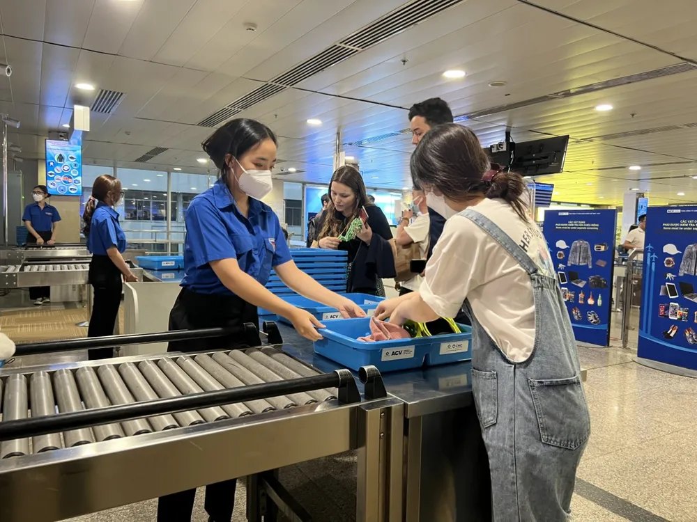 Đoàn Thanh niên Cảng Hàng không quốc tế Tân Sơn Nhất đang hỗ trợ hành khách làm thủ tục soi chiếu Đoàn Thanh niên Cảng Hàng không quốc tế Tân Sơn Nhất đang hỗ trợ hành khách làm thủ tục soi chiếu