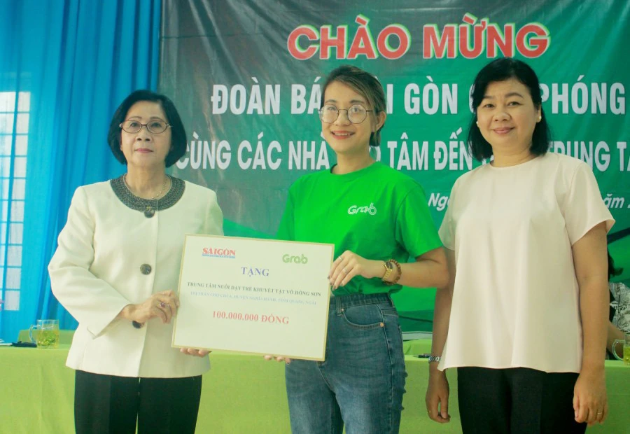 Bà Lý Việt Trung, Phó Tổng Biên tập Báo SGGP (bên phải) cùng đại diện Công ty TNHH Grab trao hỗ trợ 100 triệu đồng cho bà Nguyễn Thị Thu Hà, Giám đốc Trung tâm Võ Hồng Sơn. Ảnh: NGUYỄN TRANG