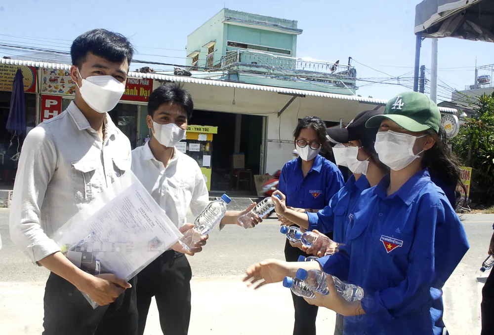 Tại điểm thi Trường THPT Vạn Tường, huyện Bình Sơn, tỉnh Quảng Ngãi, các tình nguyện viên tiếp nước cho các thí sinh trong chiều ngày 28-6. Ảnh: NGUYỄN TRANG