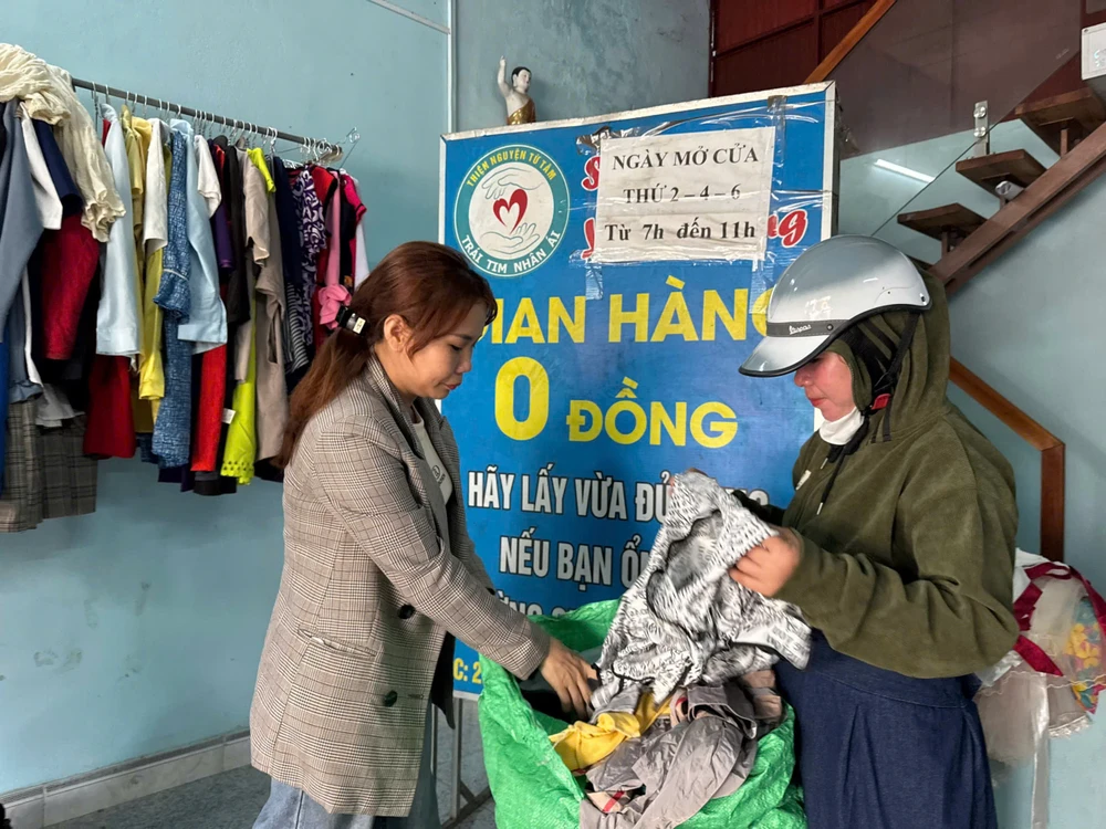 Chị Thư (bên trái) đang mở bao quần áo cũ ra để sắp xếp, phân loại gian hang 0 dong (10).jpg