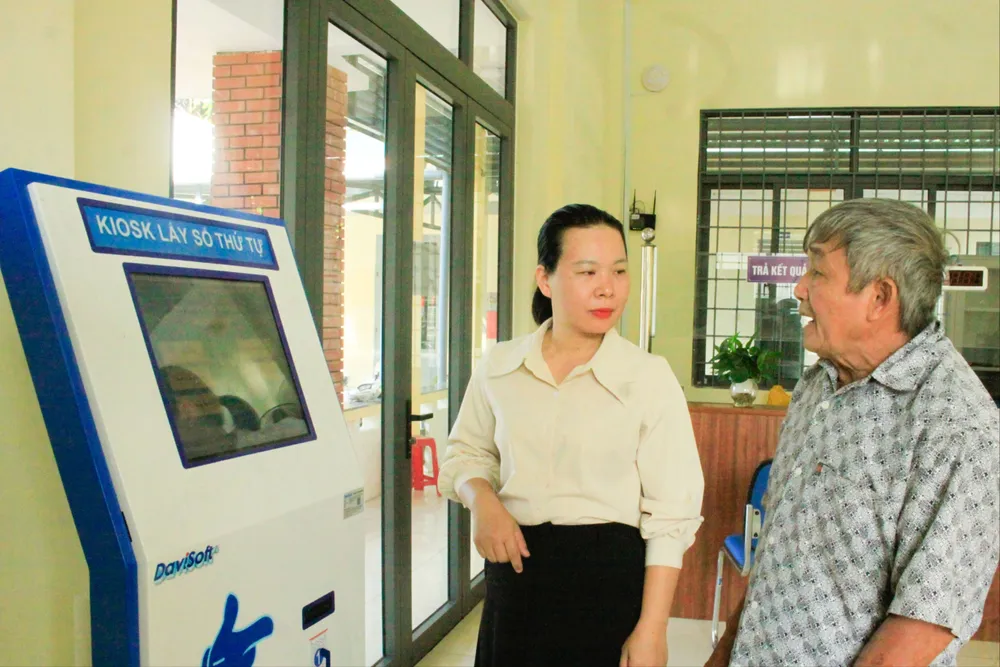 Cán bộ hướng dẫn người dân cách lấy số thứ tự. Ảnh: NGUYỄN TRANG van tuong 4 (1 of 1).jpg