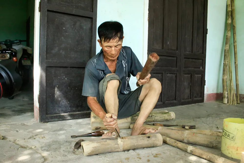 Đục lỗ trên thân tre để lắp ráp các thanh tre khi làm giường hoặc làm thang tre. Ảnh: NGUYỄN TRANG xóm giường (22).jpg