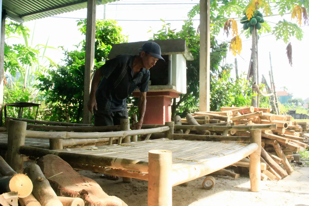 Ông An đang hoàn thành công đoạn cuối cho chiếc giường tre. Ảnh: NGUYỄN TRANG xóm giường (4).jpg