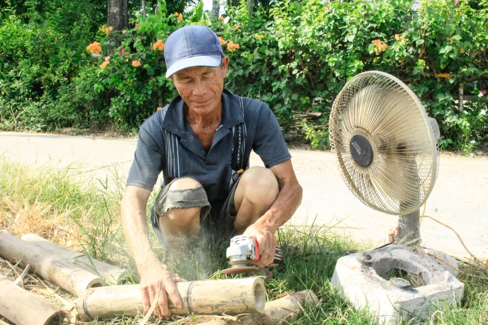 Ông Lê Văn An dùng máy mài để làm nhẵn bề mặt tre. Ảnh: NGUYỄN TRANG xóm giường (7).jpg