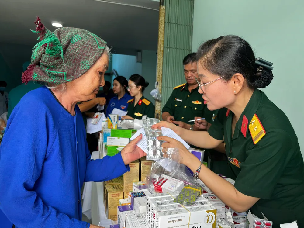 Hướng dẫn cho cụ già cách sử dụng thuốc. Ảnh: NGUYỄN TRANG phát thuốc (1).jpg