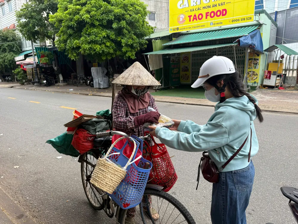 Dù là đang thu mua ve chai, người phụ nữ này cũng bất ngờ khi nhận được hộp cơm nóng. Ảnh: NGUYỄN TRANG ảnh (1).jpg