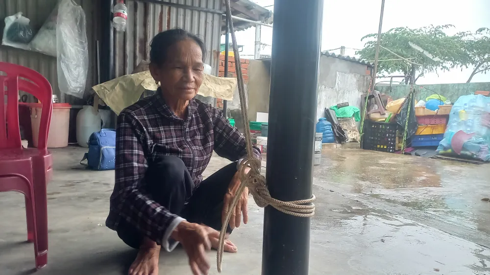 Bà Đường cột dây chằng mái tôn vào cột nhà. Ảnh: NGUYỄN TRANG 20251022_074108.jpg