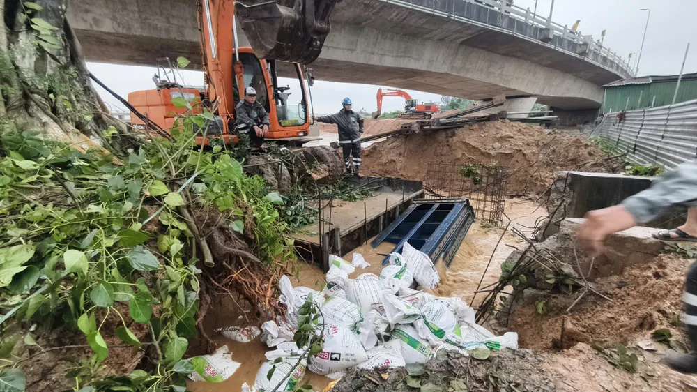 Använd en grävmaskin för att transportera järnplattan för att trycka ner brunnsbrunnen, och släpp sedan ut sandsäckar för att stoppa vattenflödet. trà khúc (9).jpg