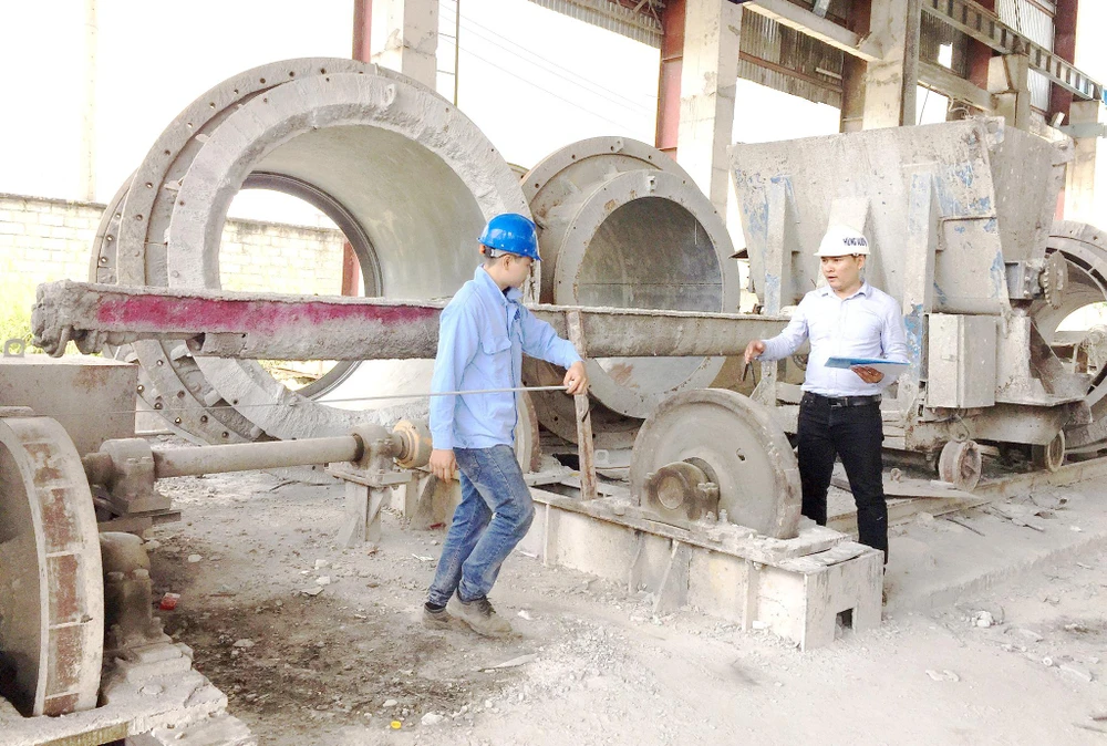 Kỹ sư Trần Quốc Toản (phải) hướng dẫn công nhân ứng dụng những cải tiến mới vào vận hành sản xuất