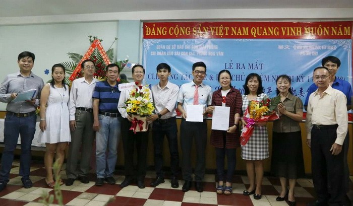 《西貢解放報》共青團書記阮祥欣（左六）和本報編委、編輯部主任范興（右一）遞交成立決定書和贈花祝賀。