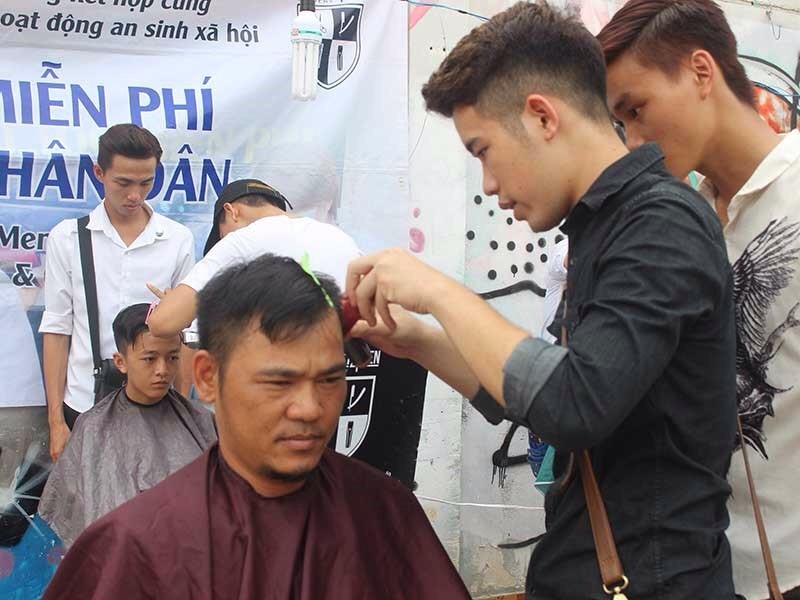 協兄邊給顧客理髮邊指導學員理髮手藝。