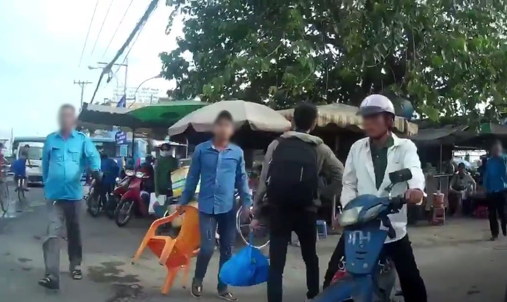 傳統“摩的”司機(藍衣)靠人多勢眾圍攻Grabike 司機。(圖源:視頻截圖)