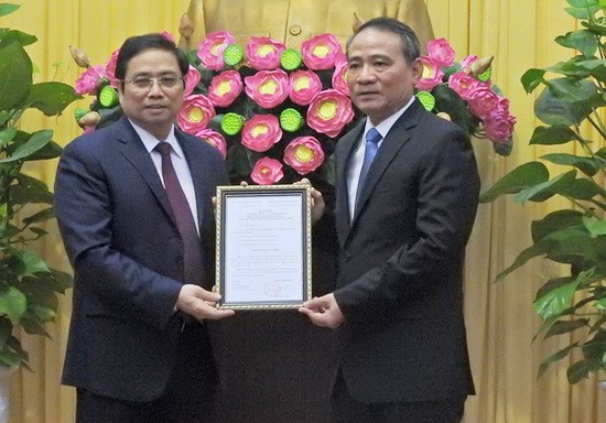 范明政同志（左）向張光義同志授予人事委任《決定》。