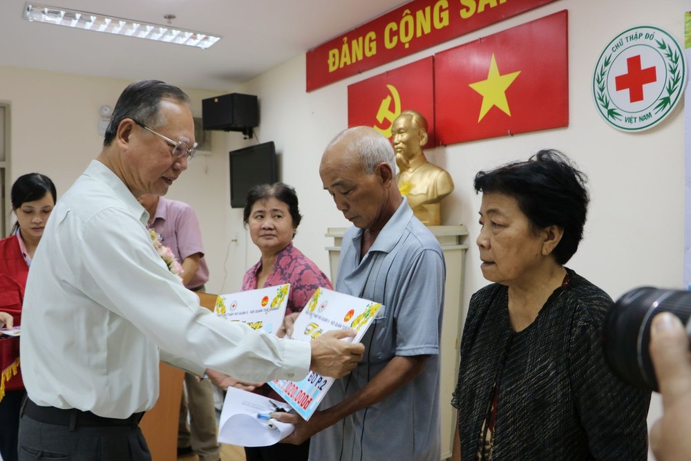 穗城會館理事長盧耀南向貧困同胞贈送醫保卡。