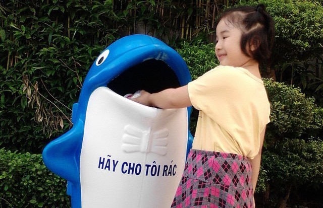 在吃完冰淇淋後，小妹妹親手把紙杯扔進垃圾桶去。