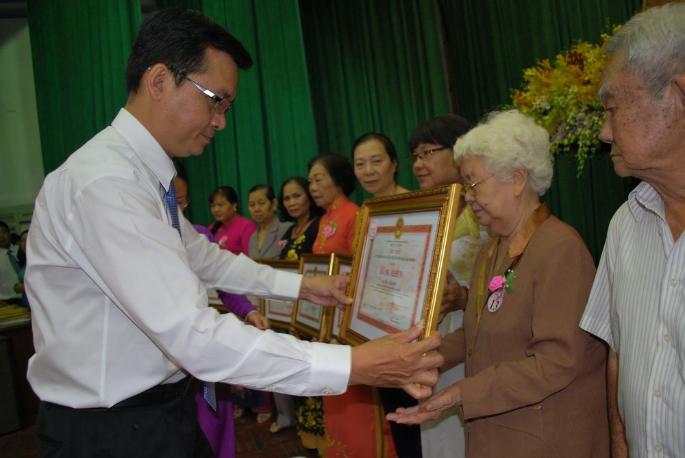 第十一郡領導向胡志堅大娘頒發市人委會獎狀。