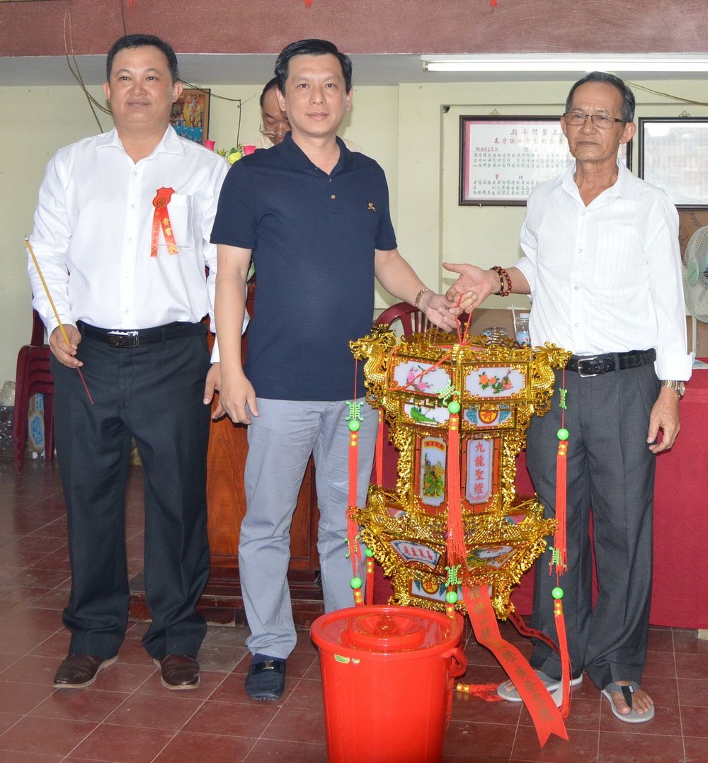 鍾振明理事長移交一本萬利聖燈給 得主勞湧福(中)。