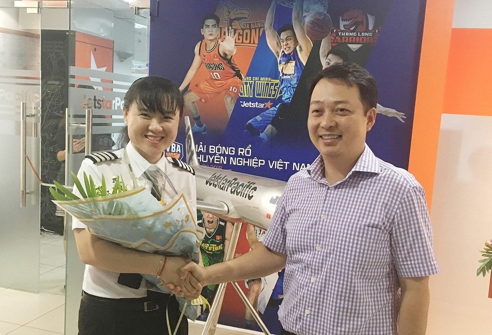 捷星太平洋航空公司代表向女機長黎氏碧紅(左)頒發機長證書並贈送鮮花祝賀。