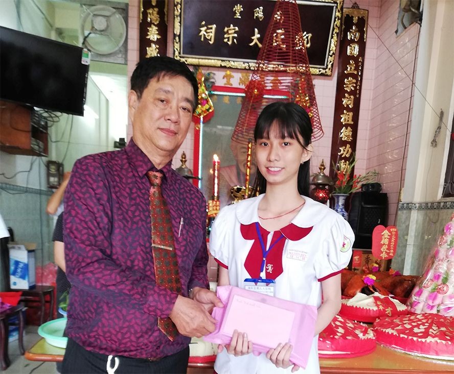 鄧氏宗祠理事長鄧榮(左)向鄧美心 特別優秀生頒發三份獎學金。