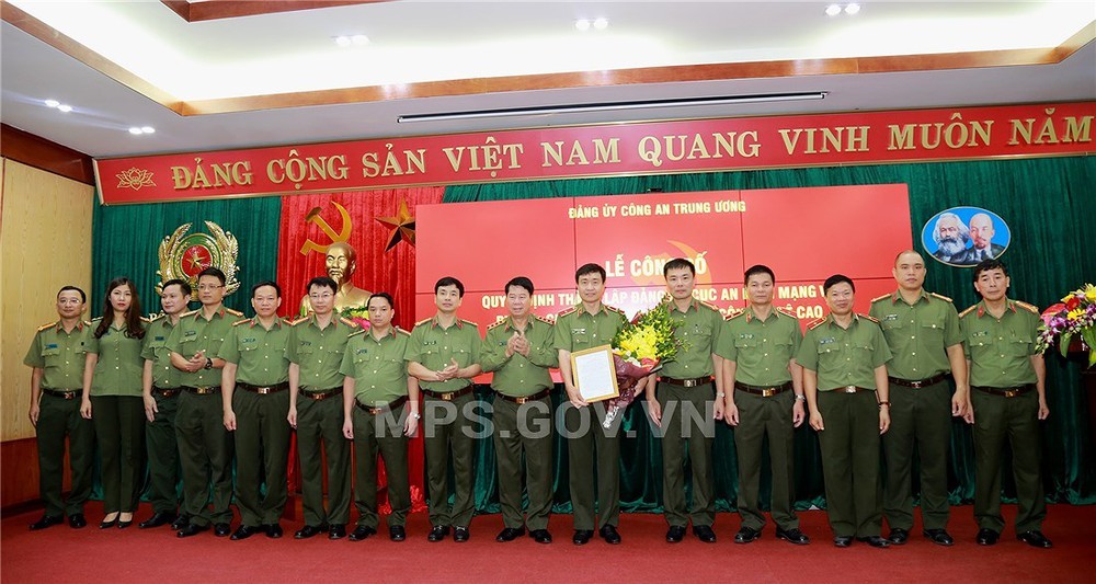 公安部副部長裴文南向阮明政少將頒授網絡安全與高科技罪犯防治警察局黨部成立《決定》並贈送鮮花祝賀後與該黨部成員合影留念。（圖源：公安部）