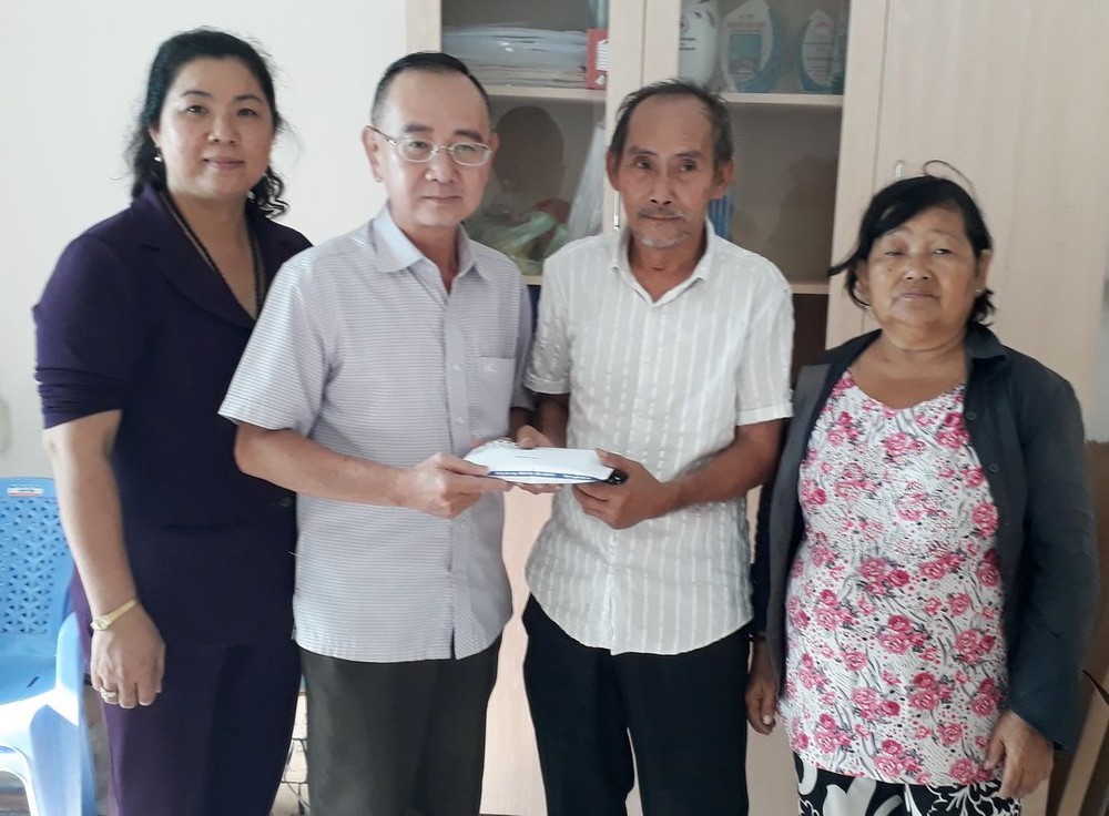 本報編委兼編輯部主任范興（左二）把讀者捐助的款項移交給戶主吳育勇、張南瑛夫婦。