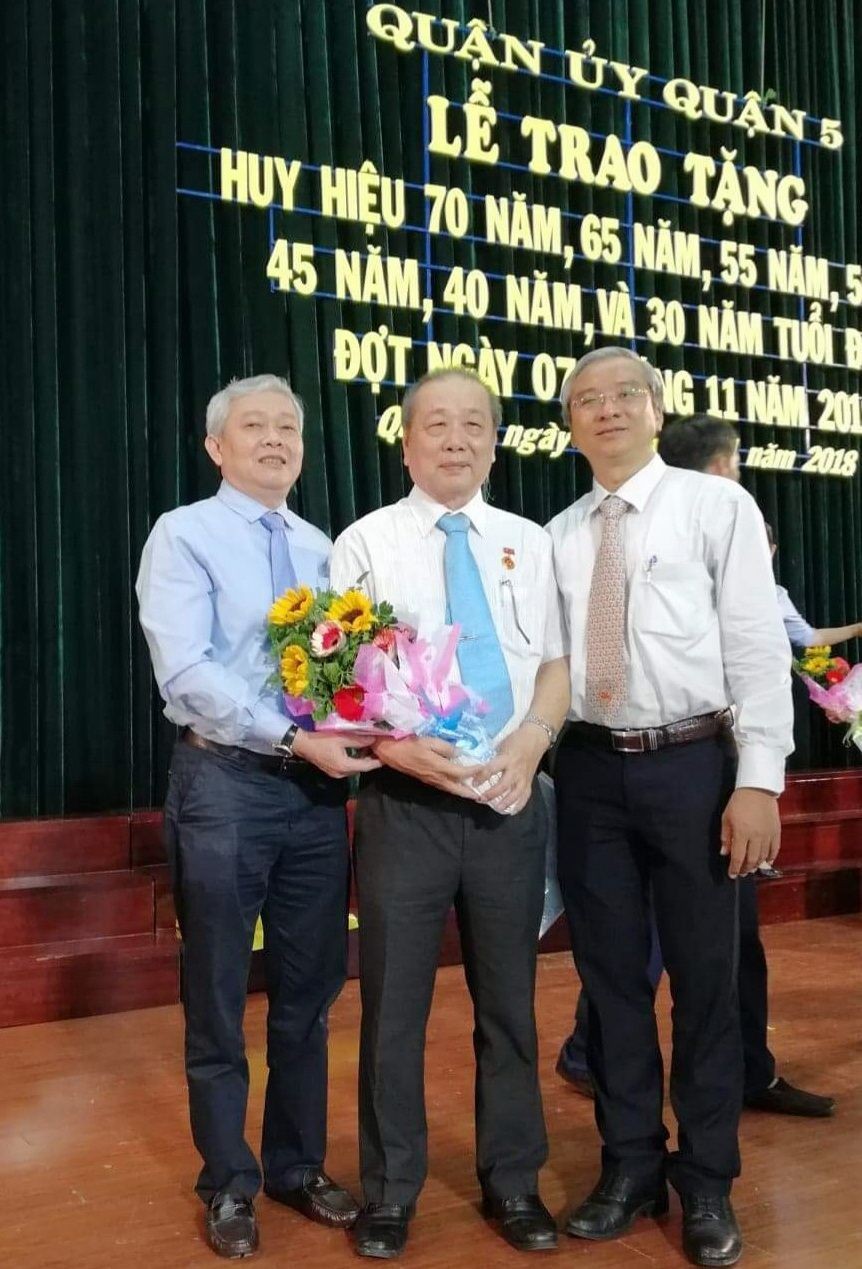 第五郡郡委書記武進仕（左）和郡人委會主席范國輝（右）送花祝賀華人黨員孫盛強。