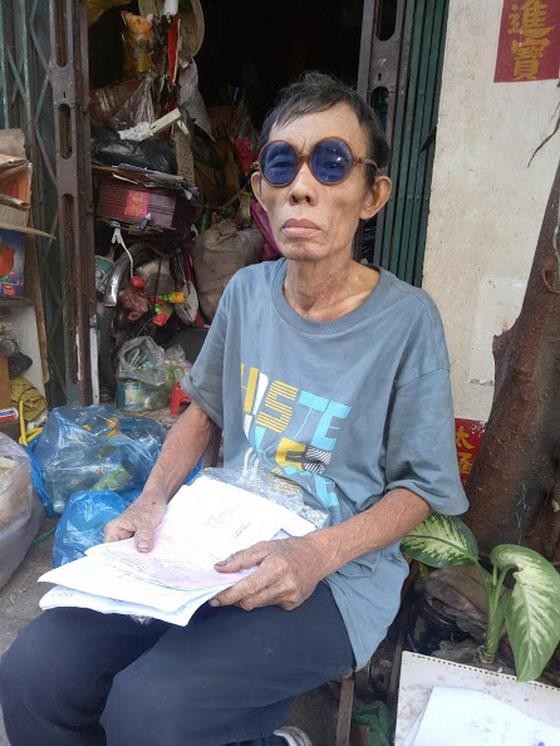 吳月貴拿著病案坐在自家門口。