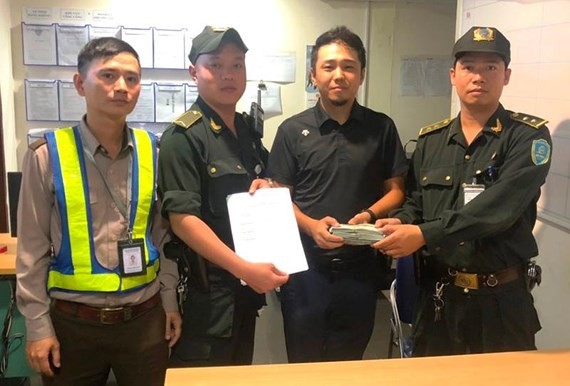 峴港國際機場航空安全中心代表人向中國籍乘客嚴光柱(音)交還遺留巨款。（圖源：黎源）