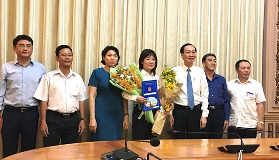 新任第八郡人委會副主席阮氏秋花同志(中)接過人事調動、批准《決定》和鮮花祝賀後與市領導合照。(圖源:孟和)
