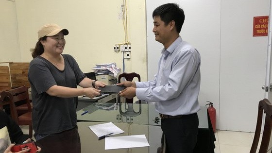 計程車公司代表將乘客遺失的錢包交還失主。（圖源：V.X）