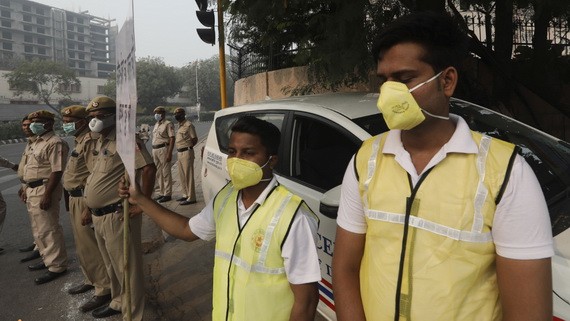 11月4日早晨，志願者和警察戴著防毒口罩站在新德里的十字路口，手舉牌子“服從單雙號限行，消除污染”。（圖源：AP）