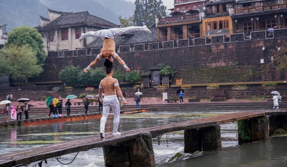 江家兄弟倆在鳳凰古鎮跨河木橋高難度頭頂頭表演一瞥。（圖源：互聯網）