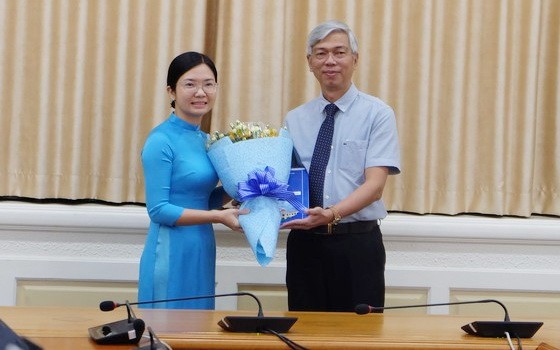 新任第六郡人委會副主席王清柳（左）從市人委會副主席武文歡手中接過人事委任《決定》和祝賀鮮花。