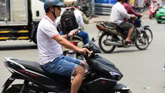 邊騎車邊拿著手機。