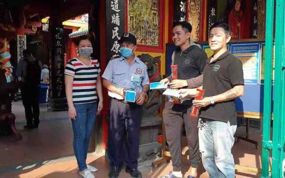 溫陵會館理事吳麗株(左一)與保安員向沒有戴口罩的善信派發口罩。