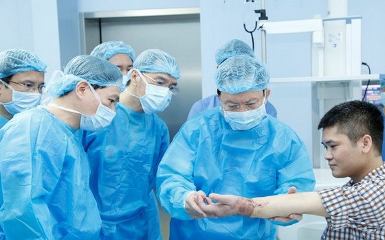 108軍隊中央醫院院長梅鴻龐教授（右二）為接受手掌移植手術後的病人檢查縫合處並評價手指伸縮機能。