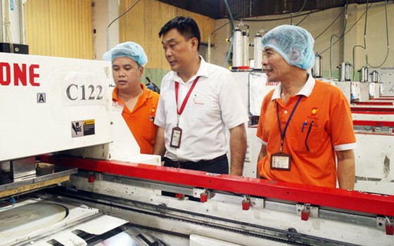 丁梅雄（中）與工人討論產品質量。