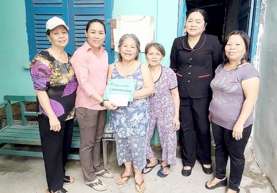 阮芳秋（左一）與地方幹部向窮困家庭發放輔助金。