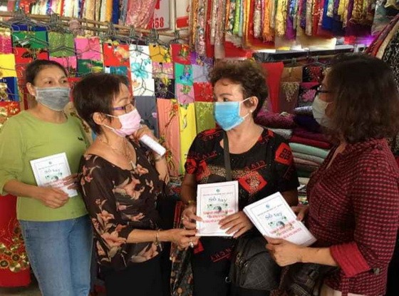 華人商販應氏蓮(左二)派發防疫手冊給商販。