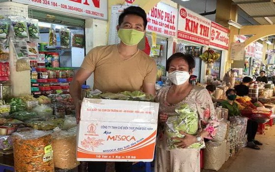 華人商販應氏蓮將防疫用品 交給阮飛雄歌星。