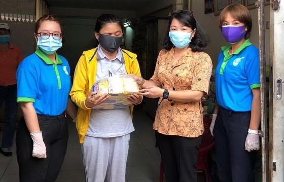 第六郡婦聯會主席梁氏菁竹(右二)向一名華人貧困者贈送禮物。