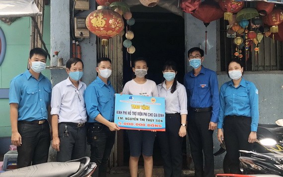 貧困青年阮玉水仙（中）從溫陵會館理事林曉東手中接過善款。