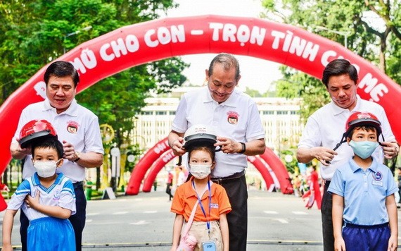 政府常務副總理張和平（中）和各位領導向小朋友們贈送安全帽。（圖源：元姮）