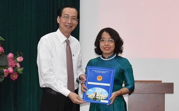 梅氏紅花同志（右）從市人委會常務副主席黎清廉手中接過人事委任《決定》。（圖源：市黨部新聞網）