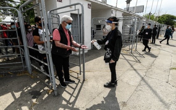 10月25日，在智利首都聖地亞哥一處投票站，一位老人在入口給手消毒。 智利25日舉行全民公投，選民們投票贊成成立“制憲會議”制定新憲法。（圖源：新華社）