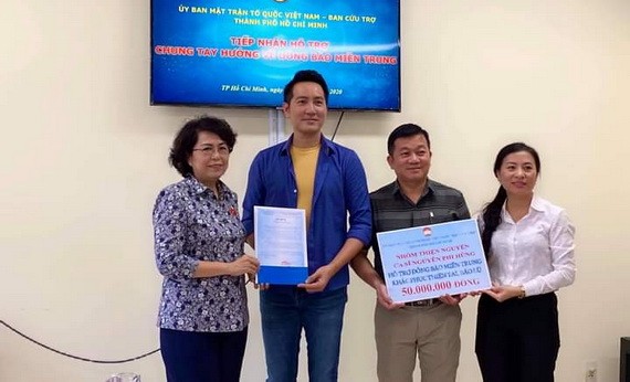 阮飛雄歌星與平西市場越華商販將善款交給市越南祖國陣線委員會領導。
